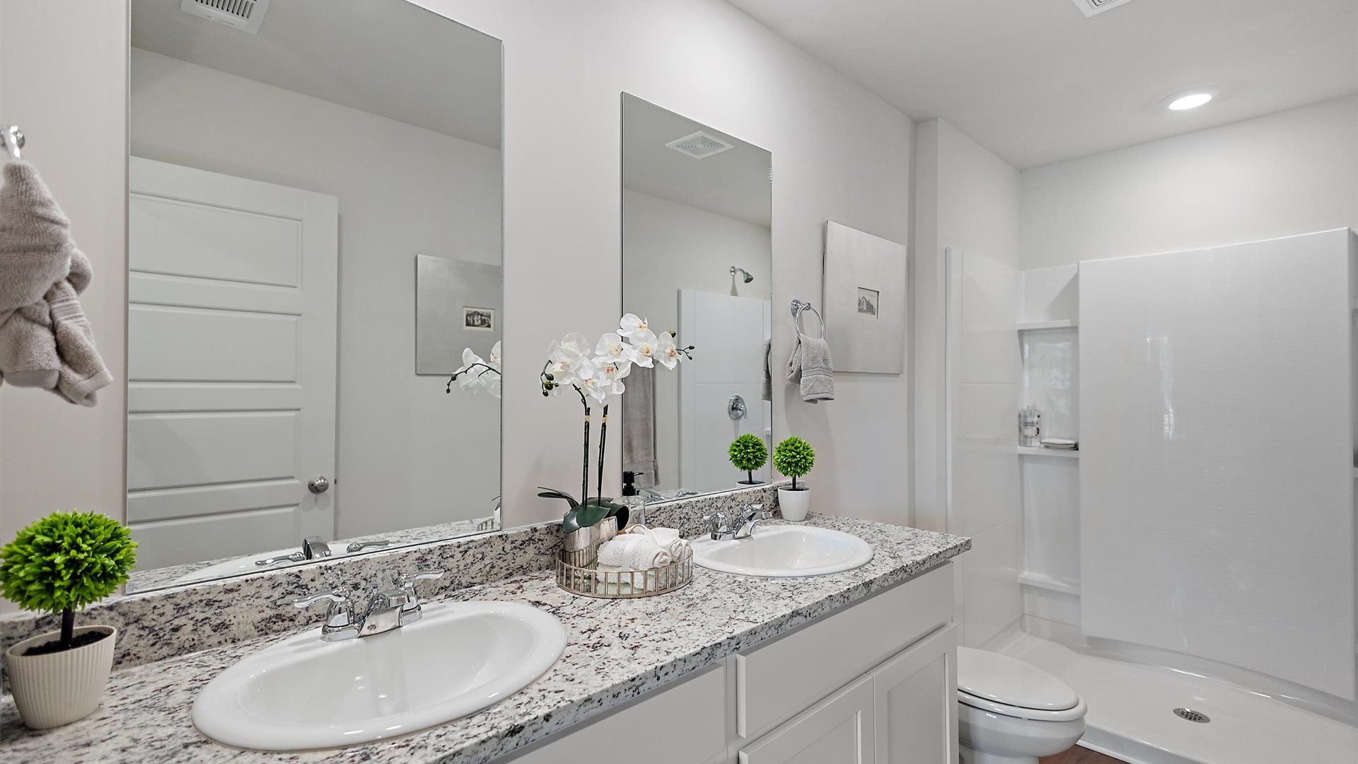 bathroom with dual vanity sinks, a toilet and a walk in shower