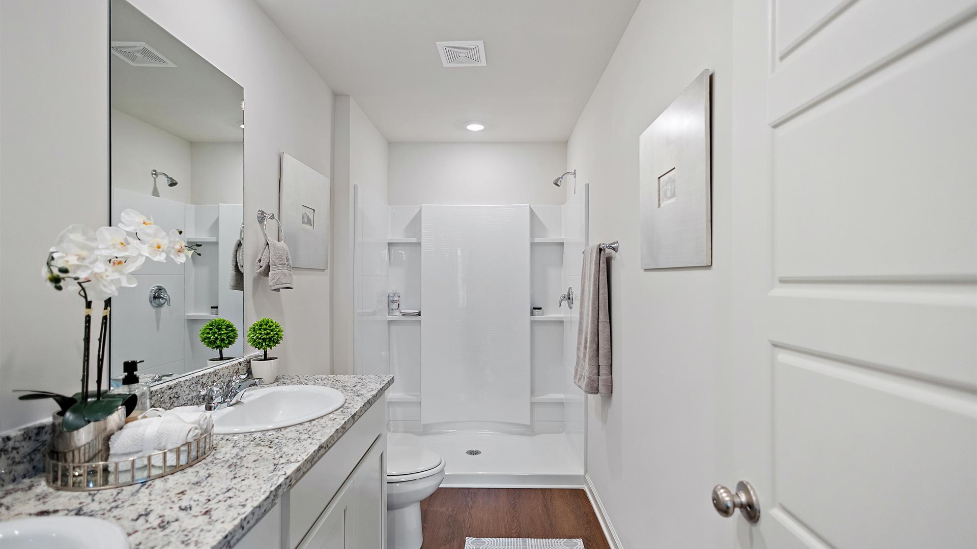 bathroom with dual vanity sinks, a toilet and a walk in shower