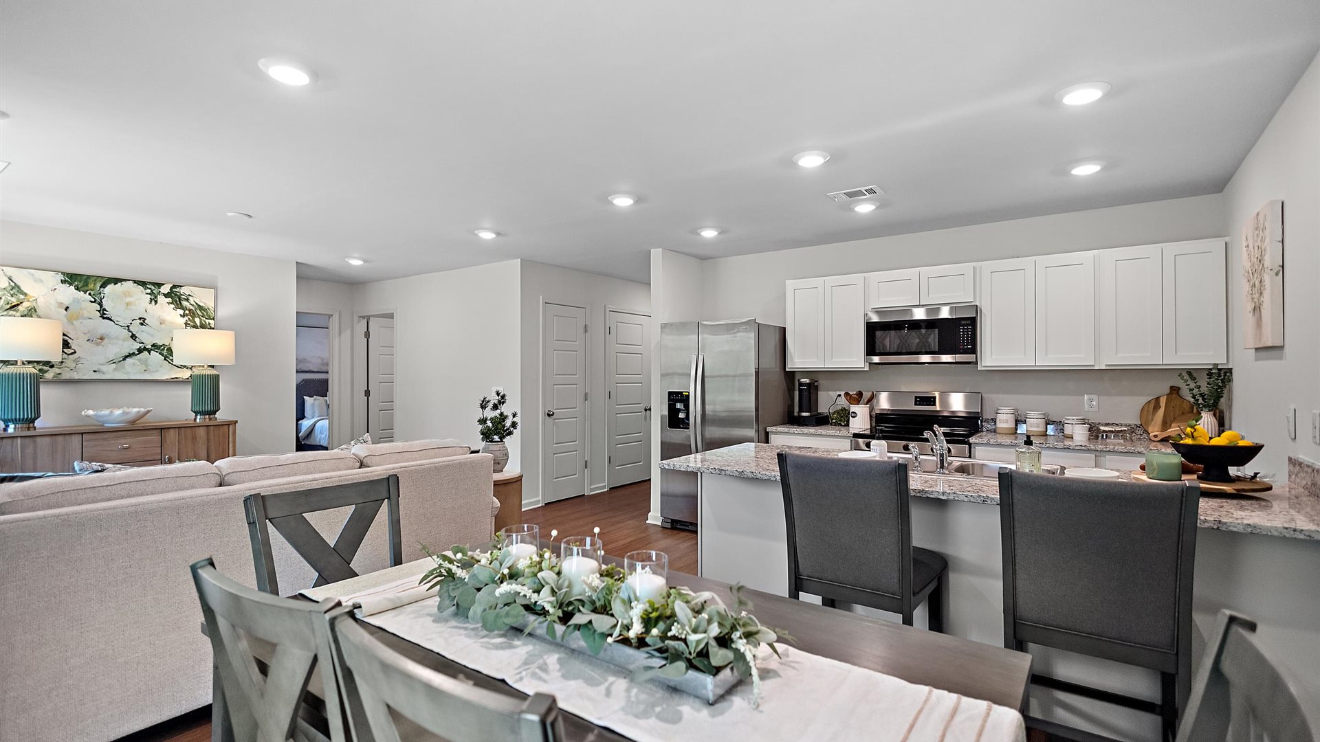 dining room with a brown rectangular table, grey rug overlooking the kitchen