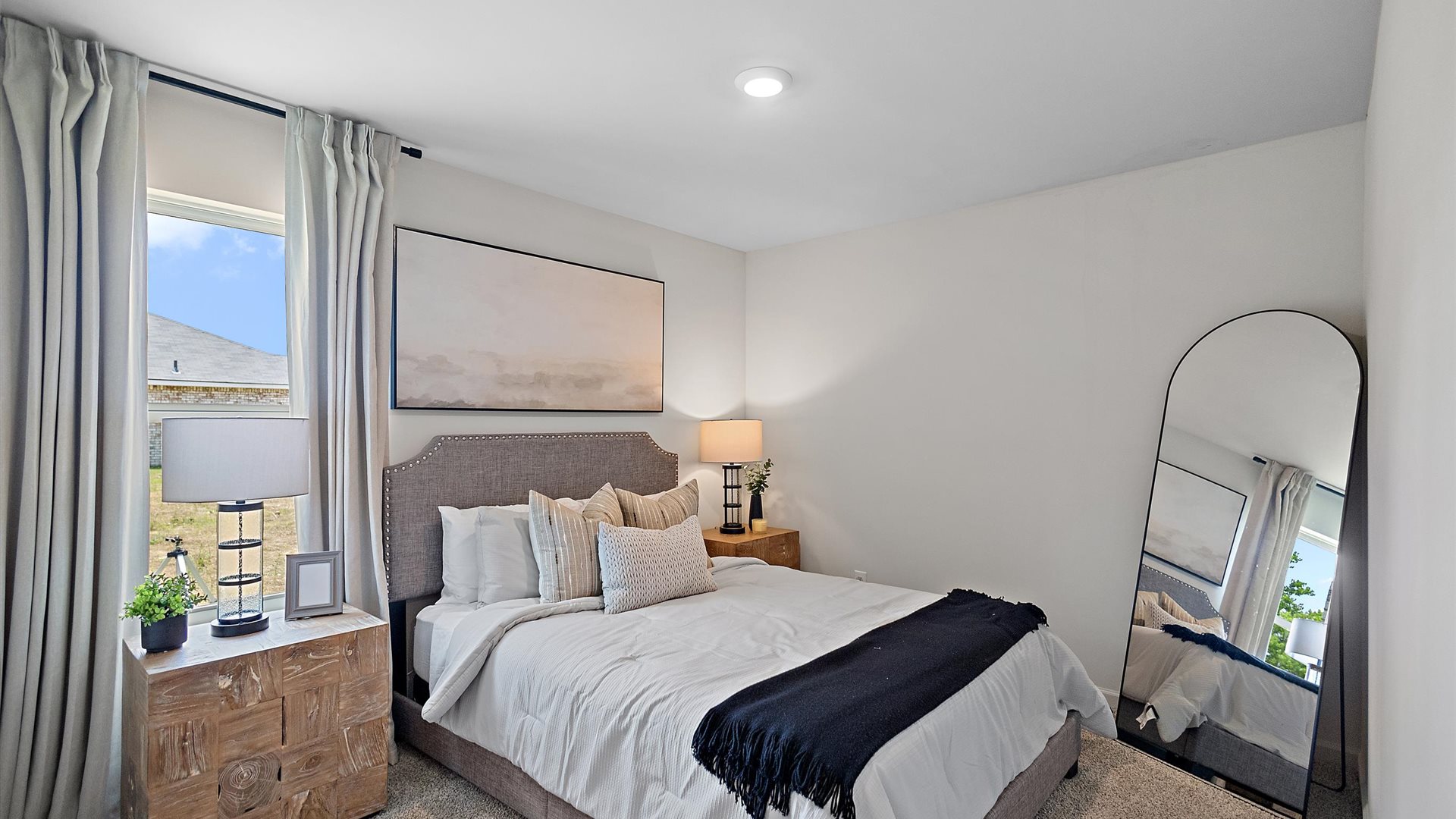 bedroom with a grey bed, white bedding and pops of grey decor