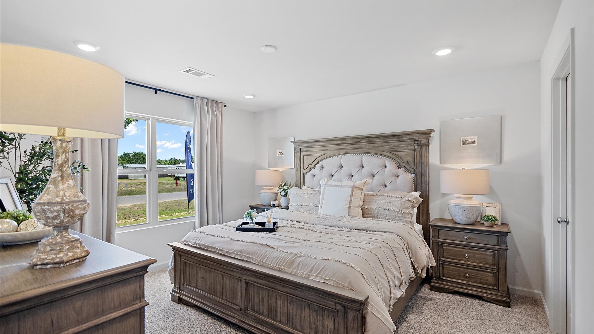 bedroom with a wooden bed, with beige bedding, and a large window