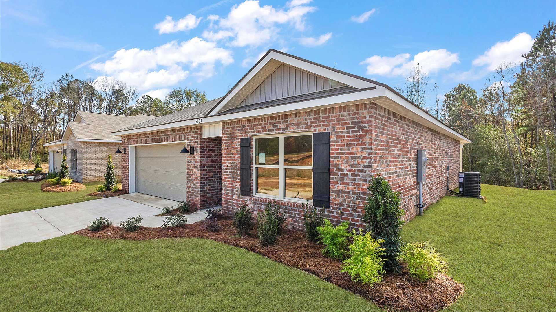 Other side exterior single story home with multi color brown brick and white paneling and brown shutters on the windows with side walk to the front door. The two-car garage and driveway.