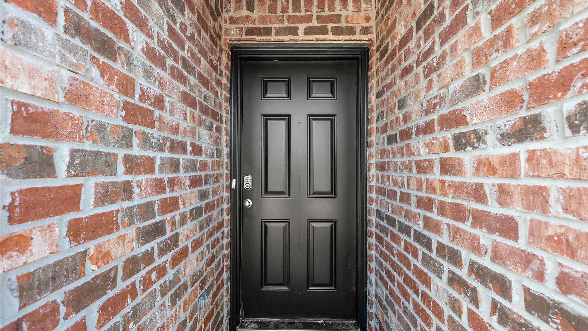 Front porch with multi color brown brick and navy door.