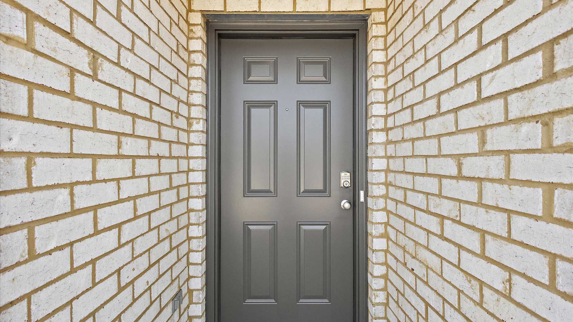 Front porch with multi color brown brick and navy door.