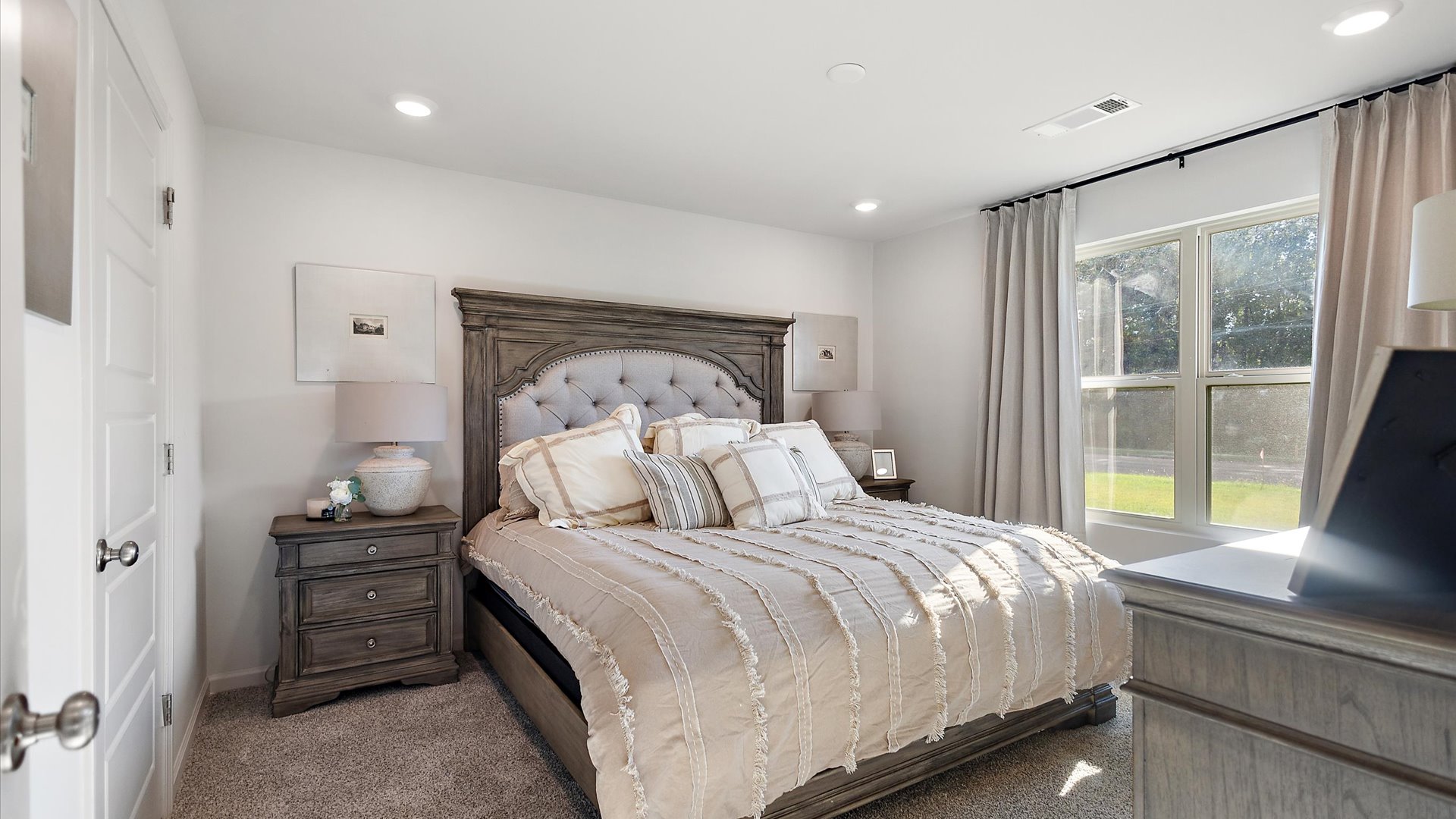 Primary bedroom with carpeted floors and window for natural light