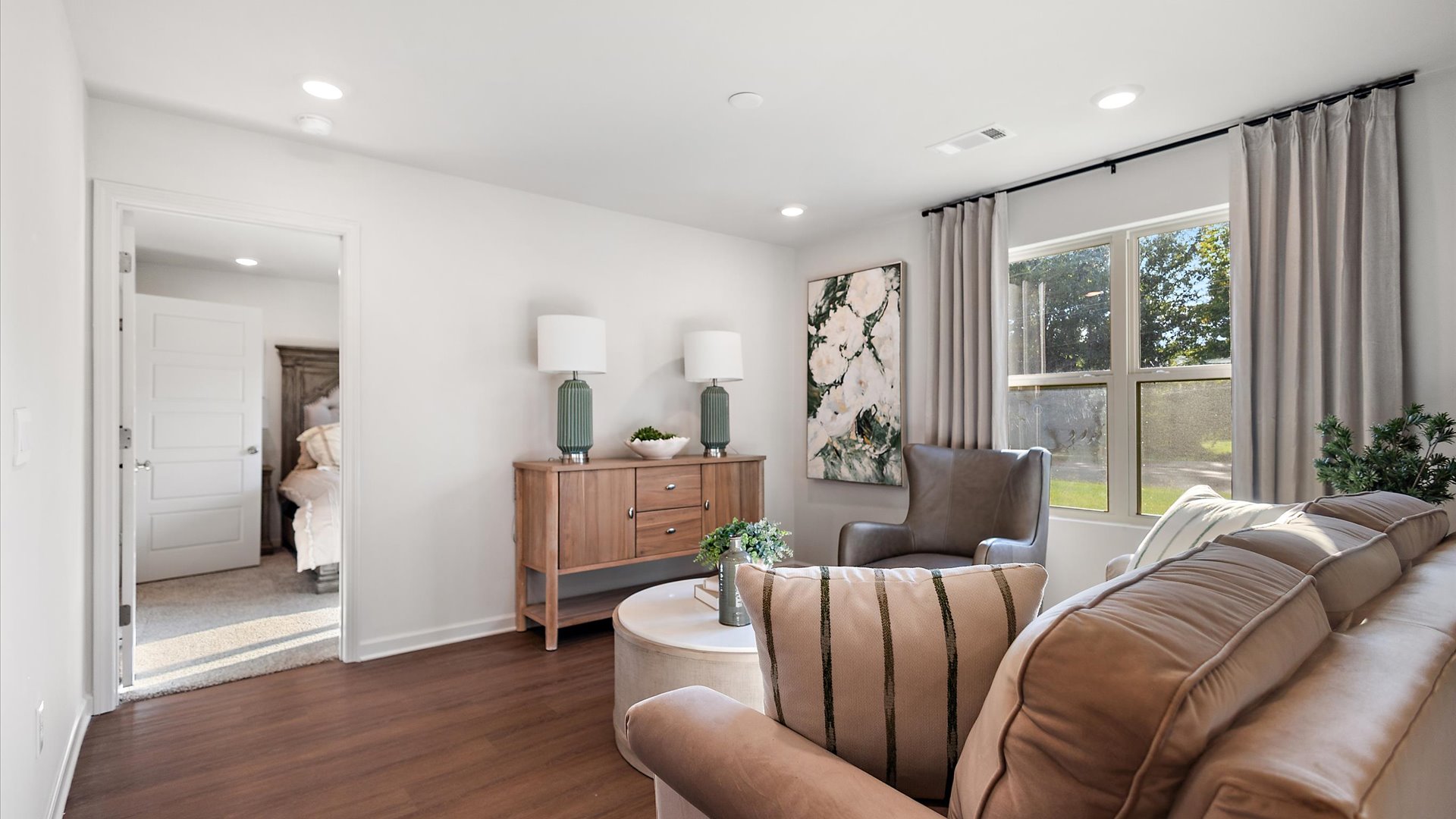 Main living space with hardwood floors, window, and entry to primary bedroom