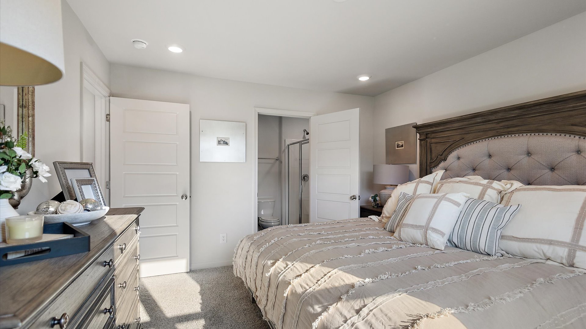 Primary bedroom with carpeted floors, recessed lighting, and door leading to primary bath