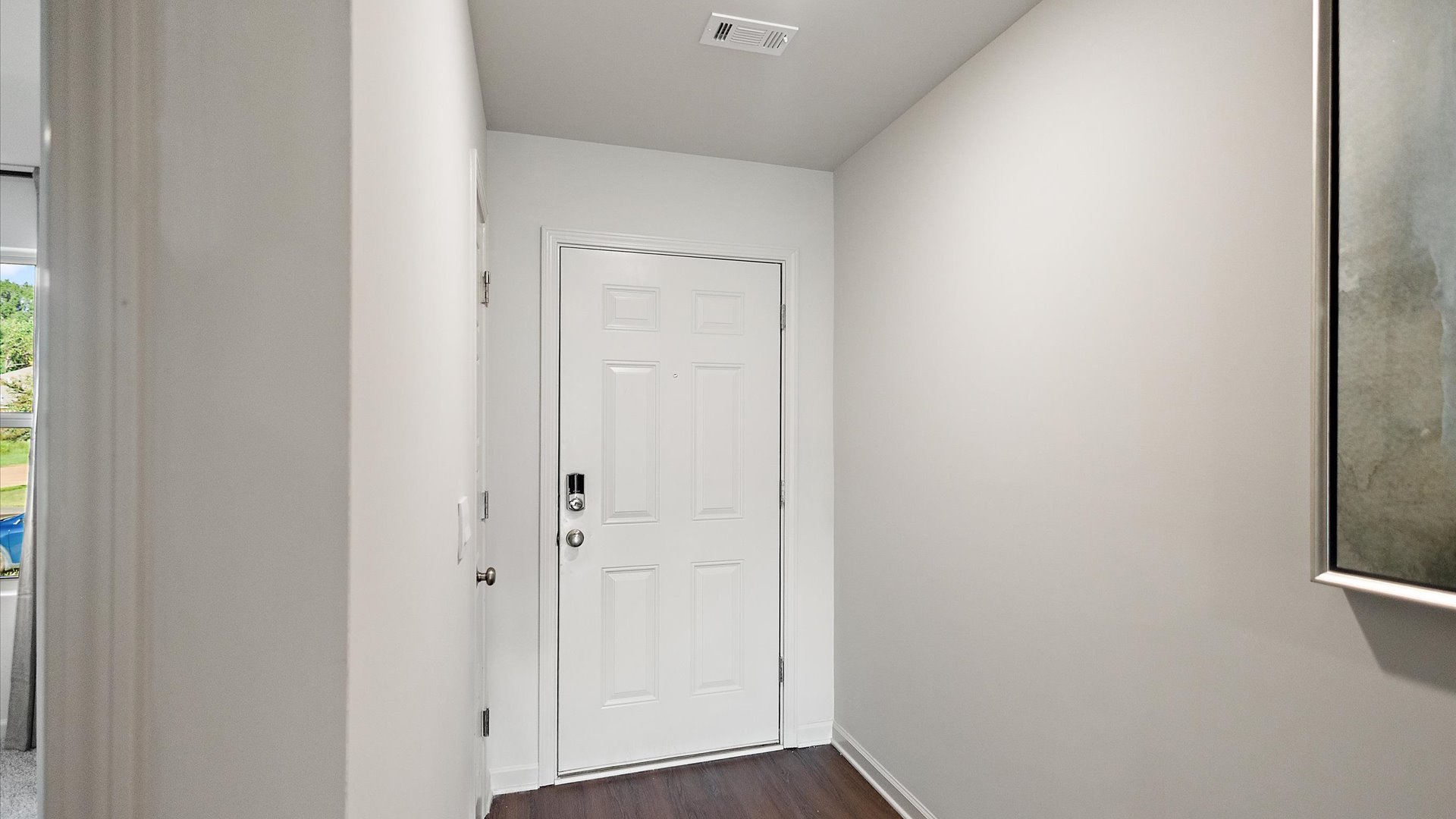 Front entryway and foyer with hardwood floors and door to the garage on the left.