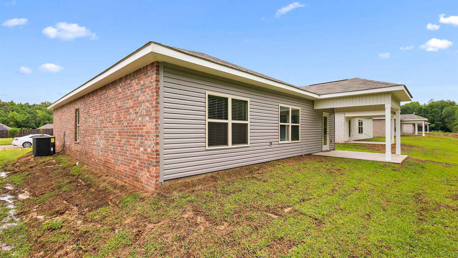 Back exterior of the side of the house and the covered patio opening up the backyard.