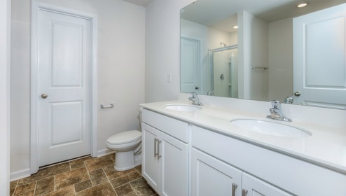 Primary bathroom with double sinks, white cabinets and counters