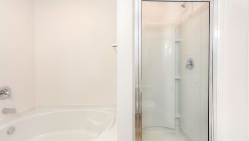 Primary bathroom with large bathtub and standing glass door shower combination