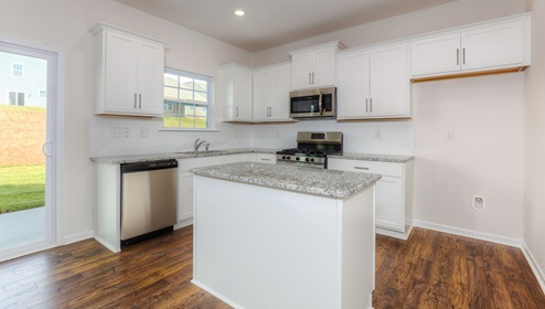 Kitchen and island with white cabinets, subway tile backsplash, and stainless steel appliances