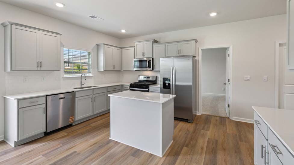 Open concept kitchen with white cabinets and counter tops and stainless steel appliances