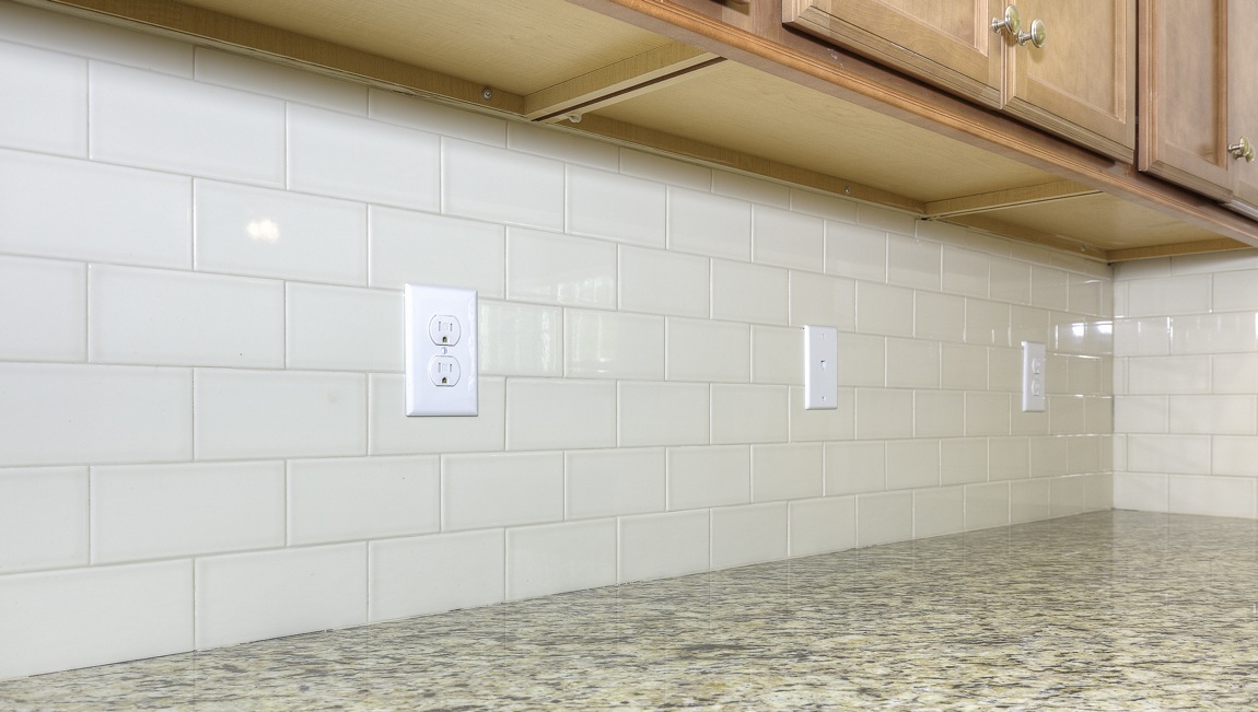 Open kitchen with brown cabinets, white subway tile backsplash, and stainless steel appliances