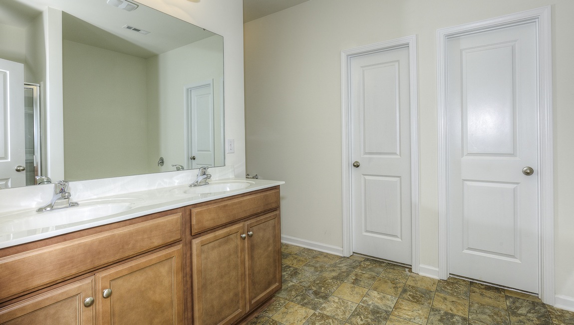 Primary bathroom with brown cabinets, and double sinks