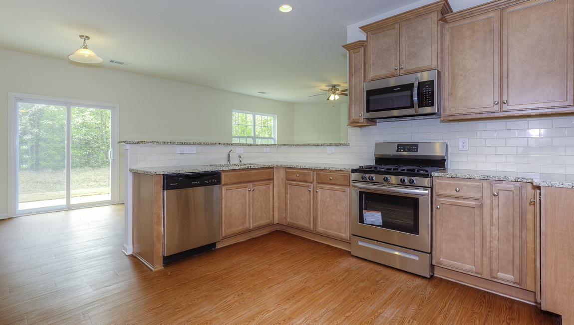 Open kitchen with brown cabinets, white subway tile backsplash, and stainless steel appliances
