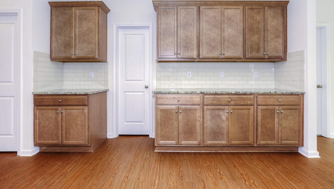 Open kitchen with brown cabinets, white subway tile backsplash, and stainless steel appliances