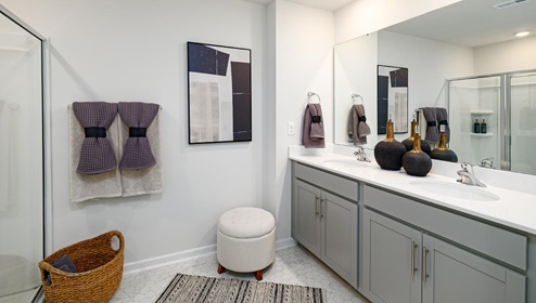 Primary bathroom with double sink vanity, grey cabinets, and standing glass door shower. New Home in Charlotte, North Carolina