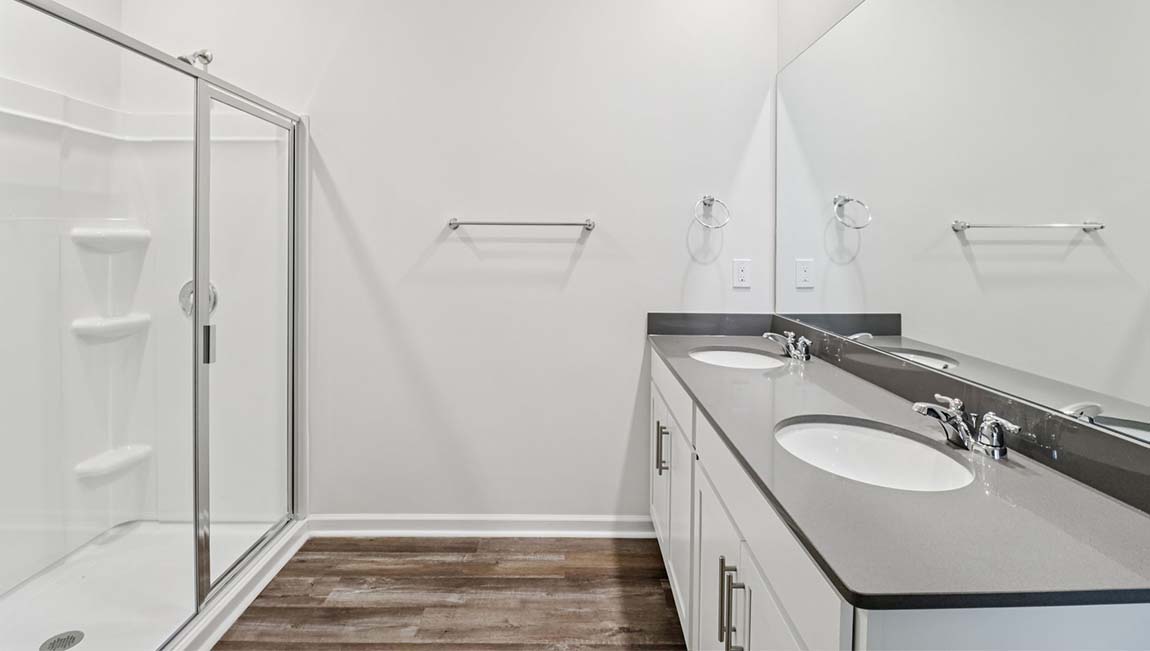 Bathroom with white cabinets and counters, double vanity, and glass door shower