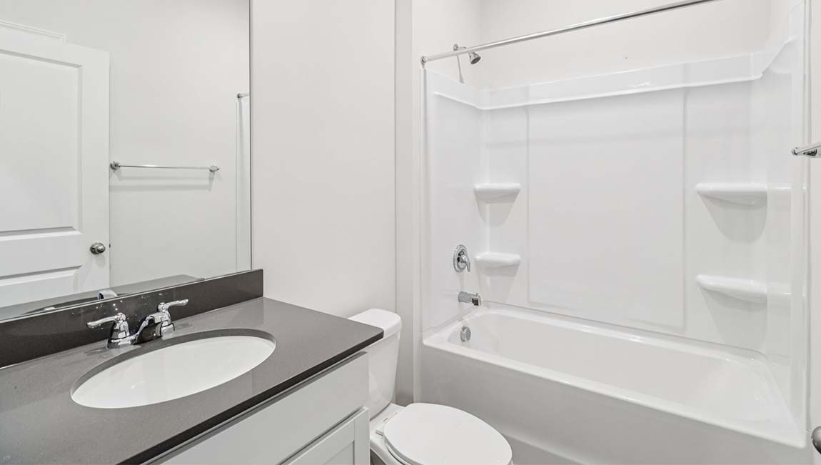 Bathroom with white counters and cabinets, and bathtub and shower combination