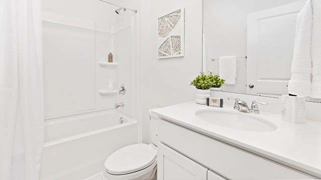 Bathroom with white counters and cabinets, and bathtub and shower combination