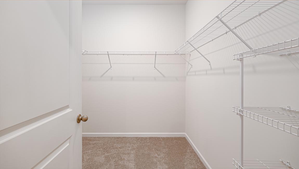 Carpeted walk in closet with hanging racks