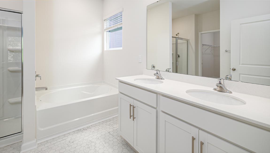 Bathroom with white cabinets and counters, double vanity, and glass door shower