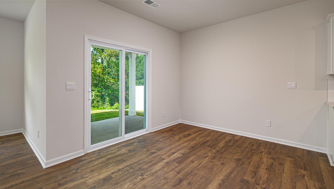 Dining area beside kitchen and living room with large windows and sliding glass back door