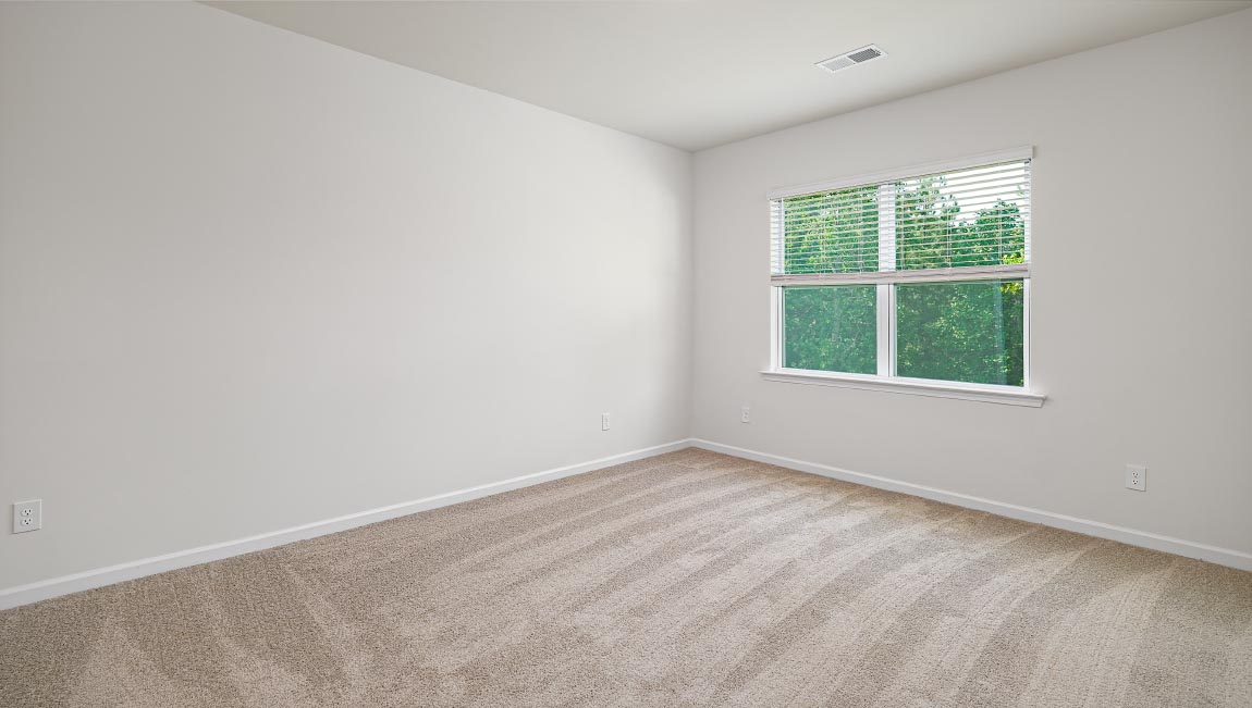 Carpeted primary bedroom with large window and ceiling fan