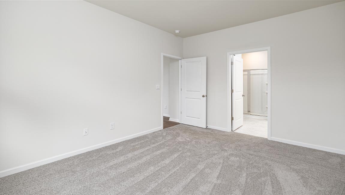 Carpeted primary bedroom with large window and ceiling fan