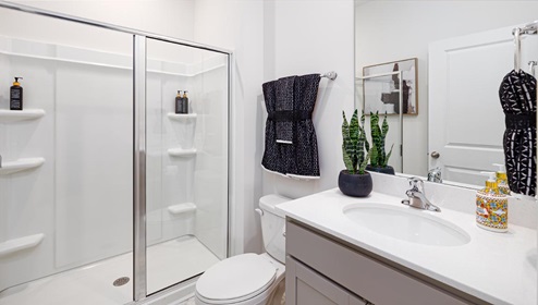 Bathroom with standing shower and grey cabinets. New Home in Charlotte, North Carolina