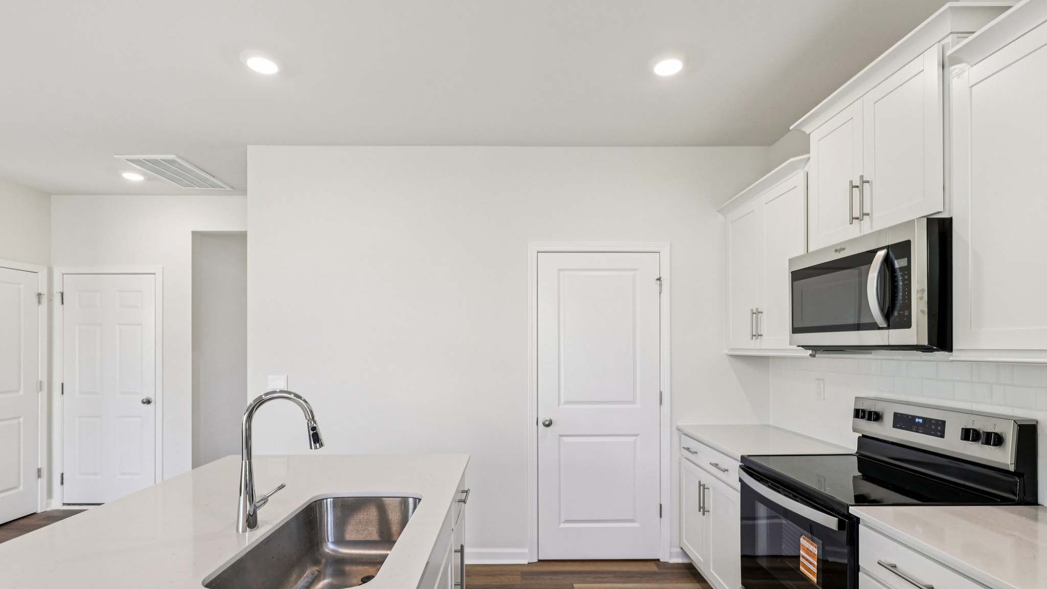 Kitchen with island, white cabinets and wood floors