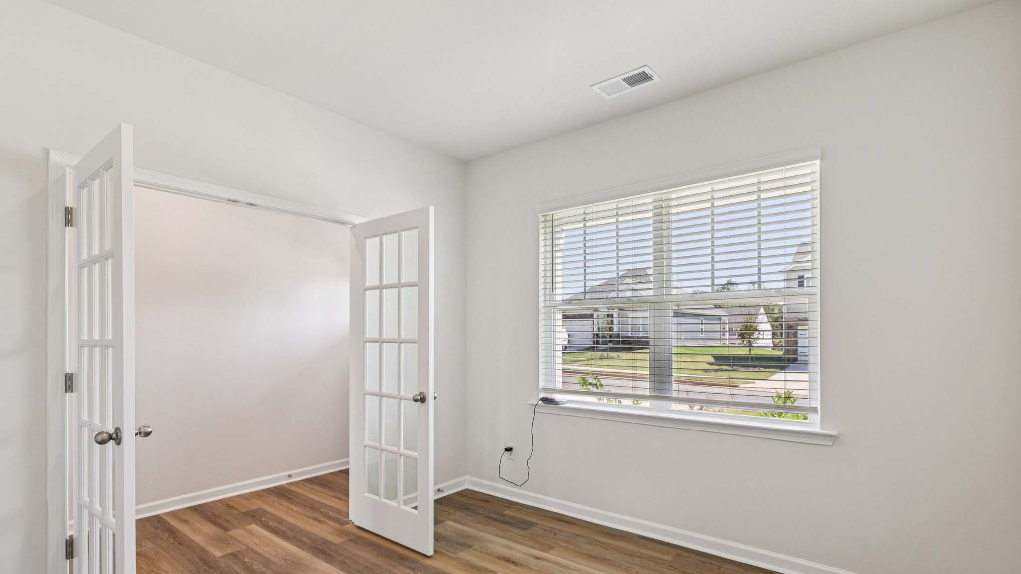 Flex office space with hardwood flooring, large window and french doors