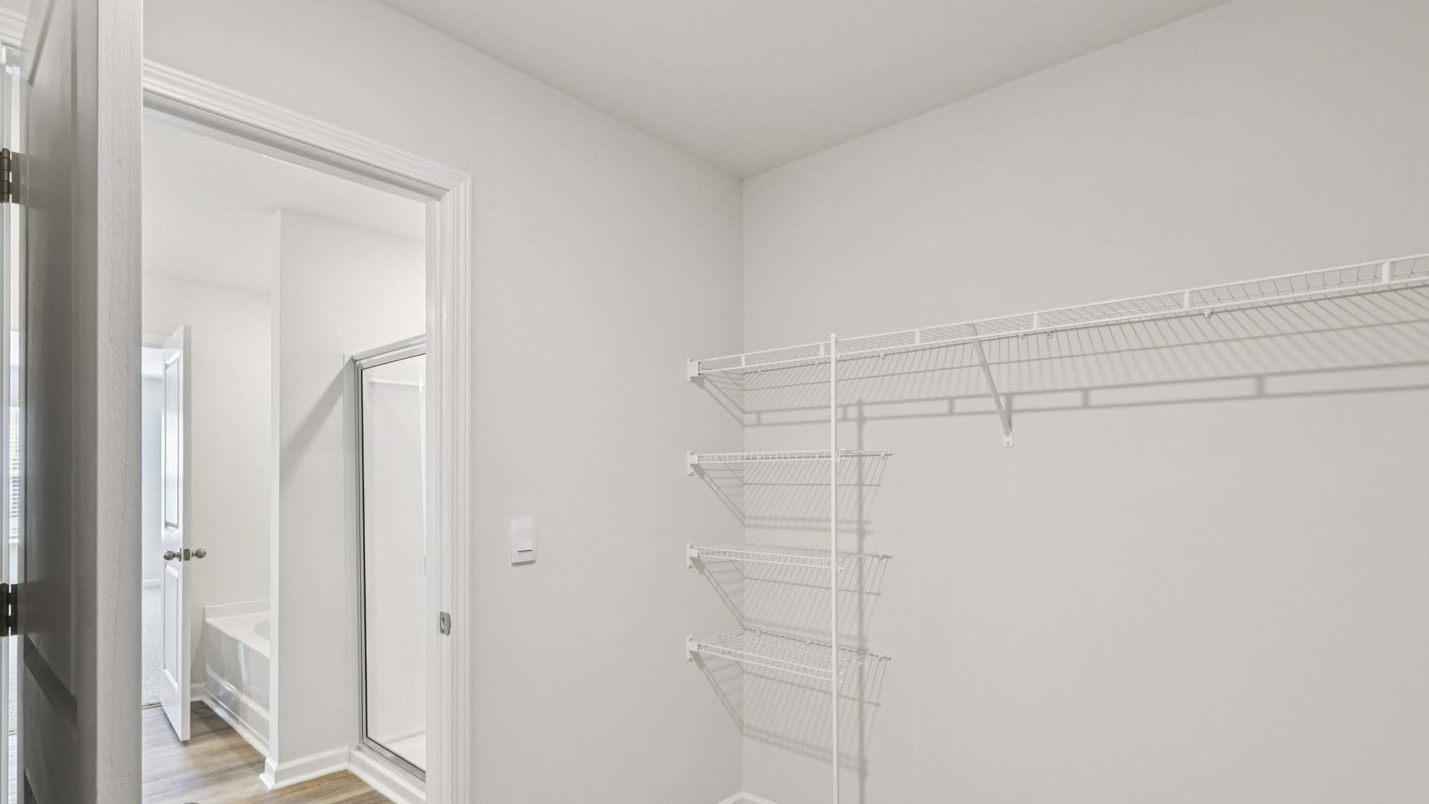 Primary walk in closet, wood floors, and racks