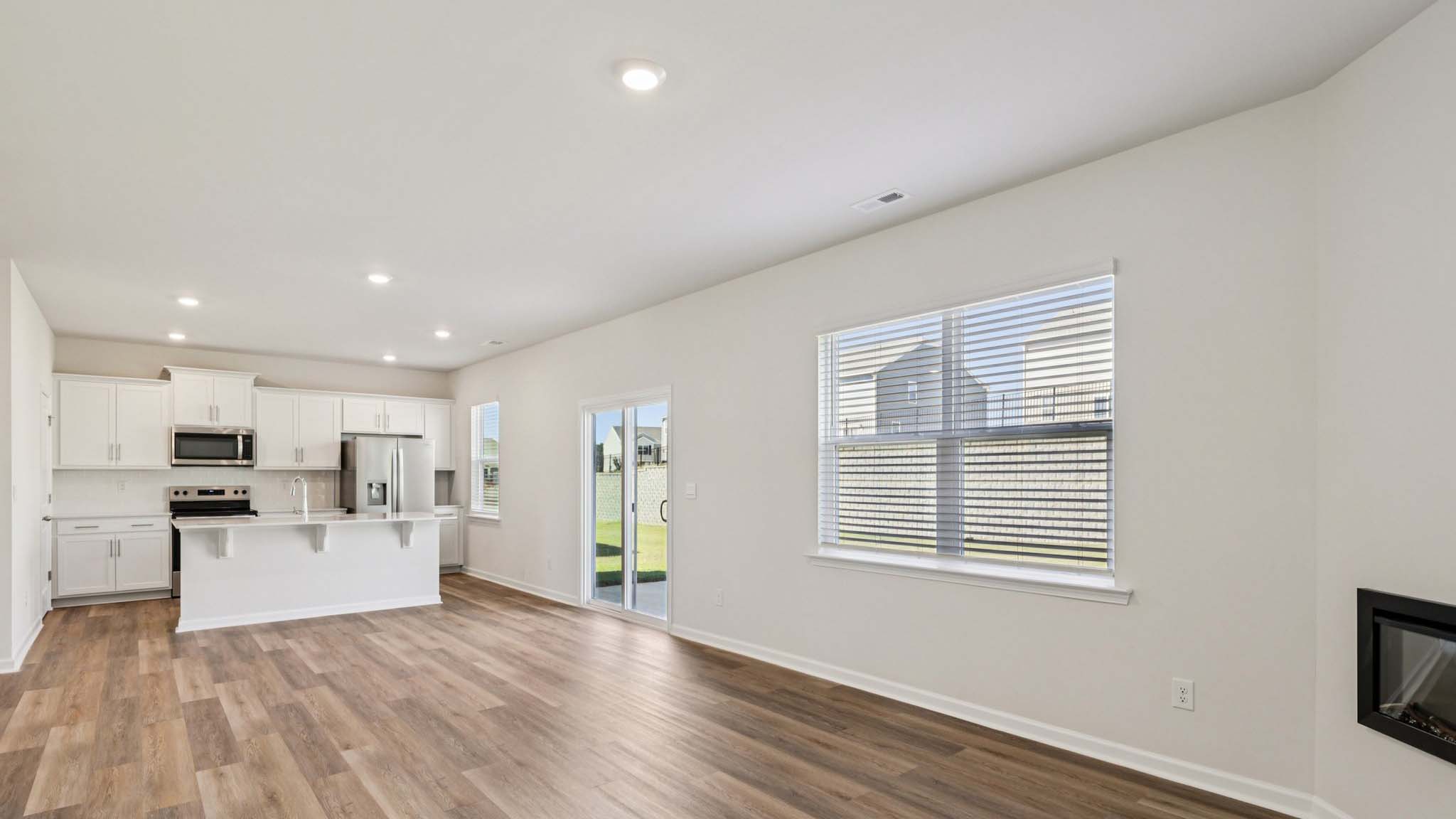 Open greatroom  beside kitchen, against staircase, with large window