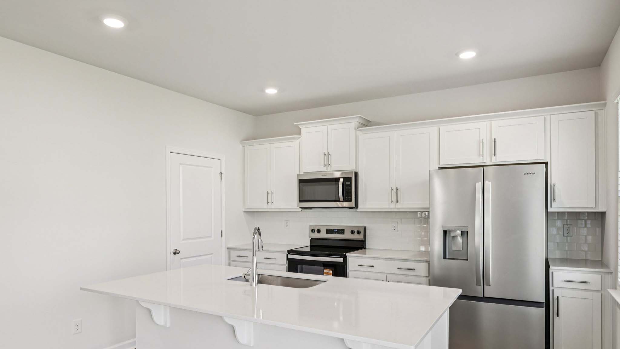 Kitchen with island, white cabinets and wood floors