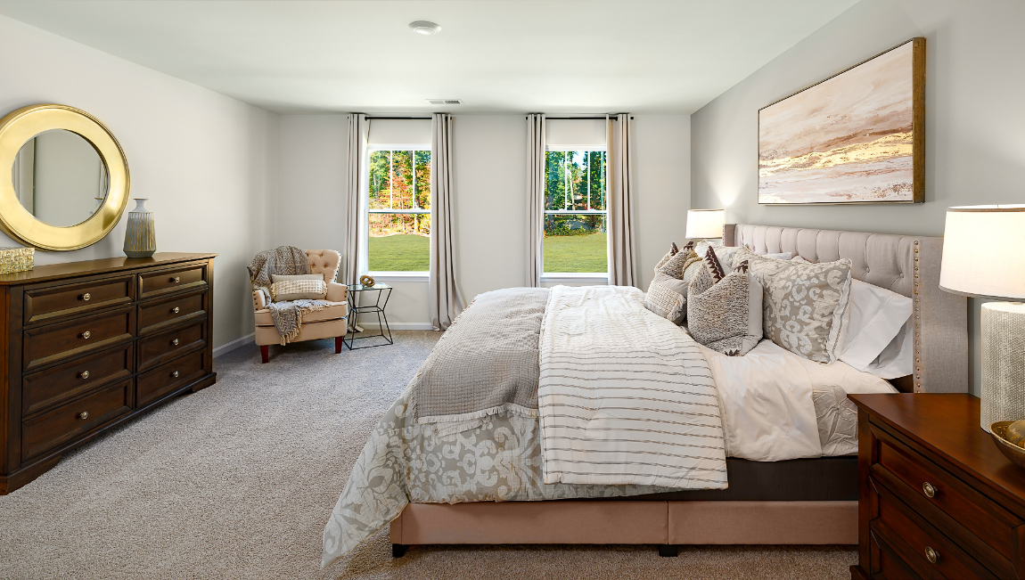 Primary carpeted bedroom with two large windows