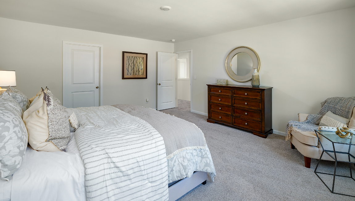 Primary carpeted bedroom with two large windows