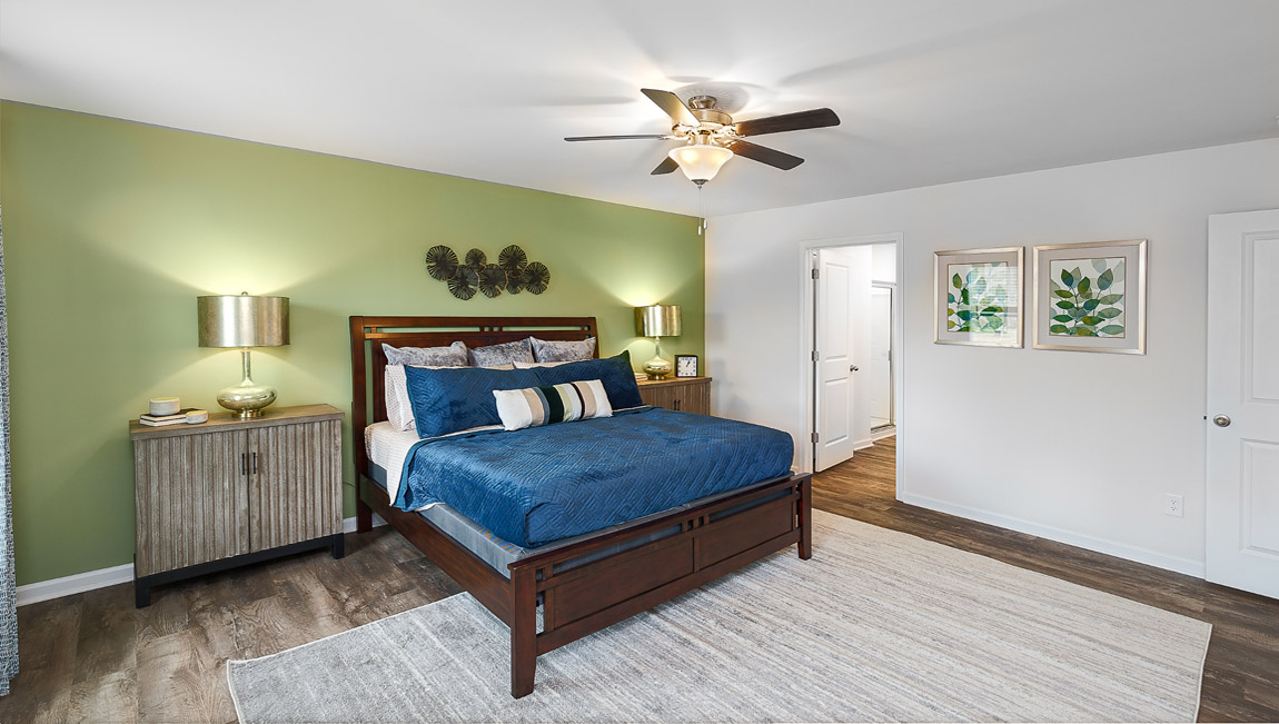 Primary bedroom with wood floors, two large windows