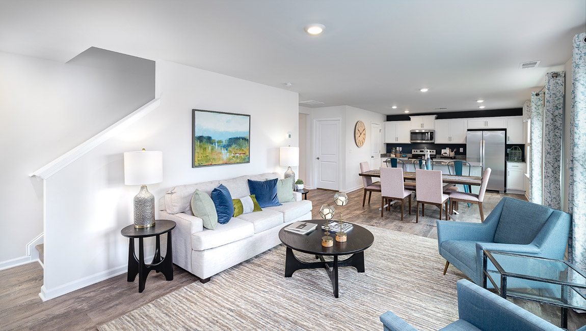 Open greatroom  beside kitchen, against staircase, with large window