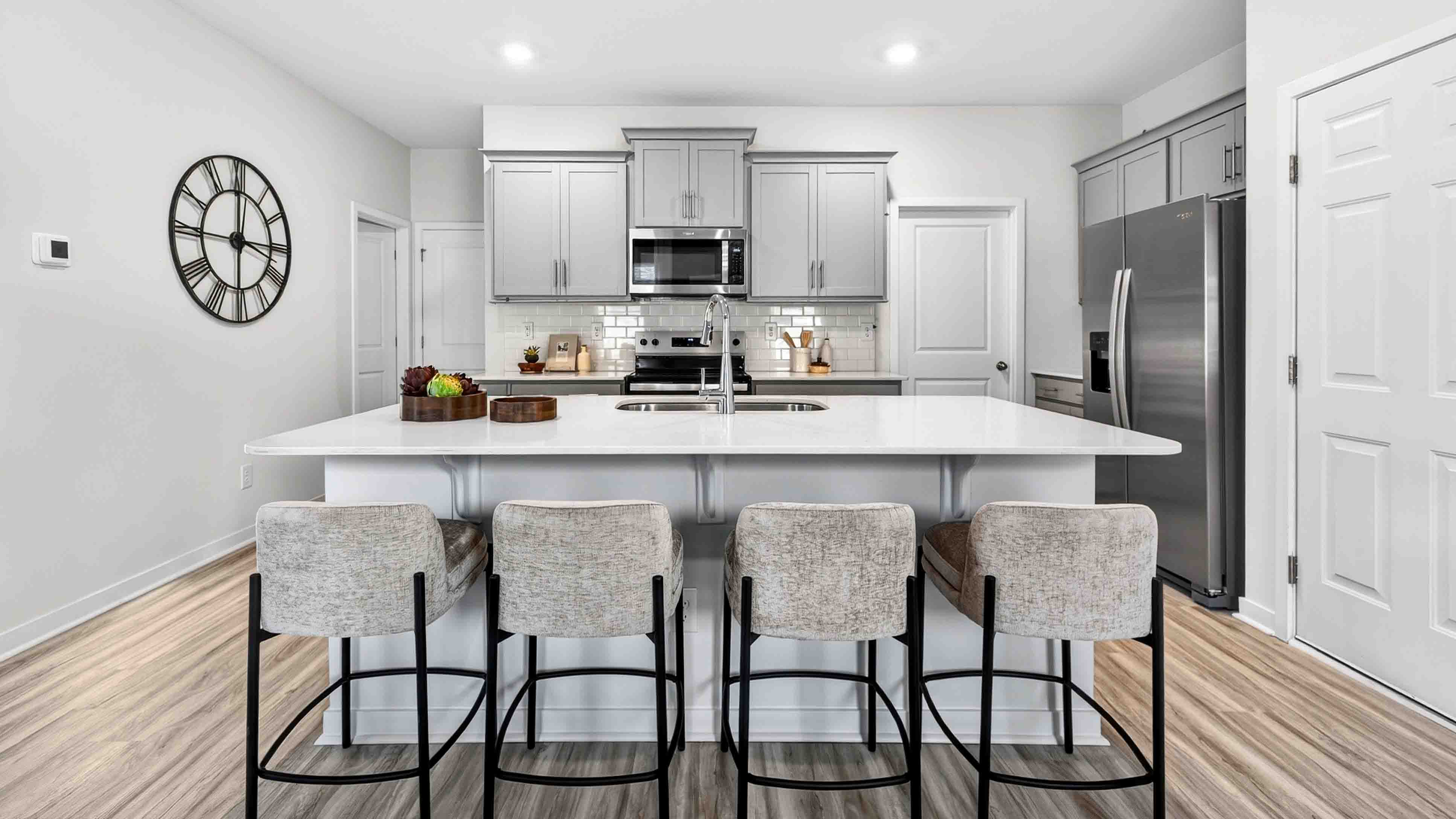 Kitchen and island with white cabinets and wood flooring