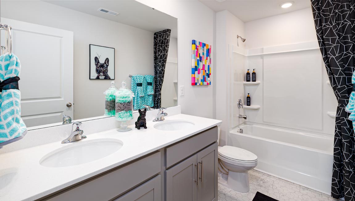 Bathroom with bathtub, double sinks, and white counters and cabinets