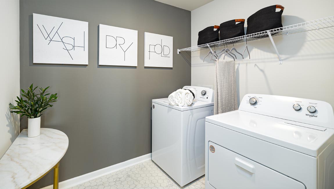 Laundry room with storage hanging racks above machines