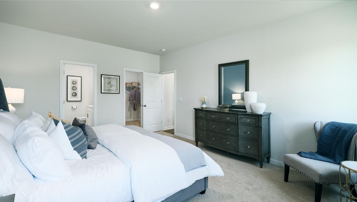 Carpeted primary bedroom with two small windows