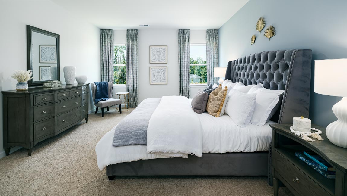Carpeted primary bedroom with two small windows
