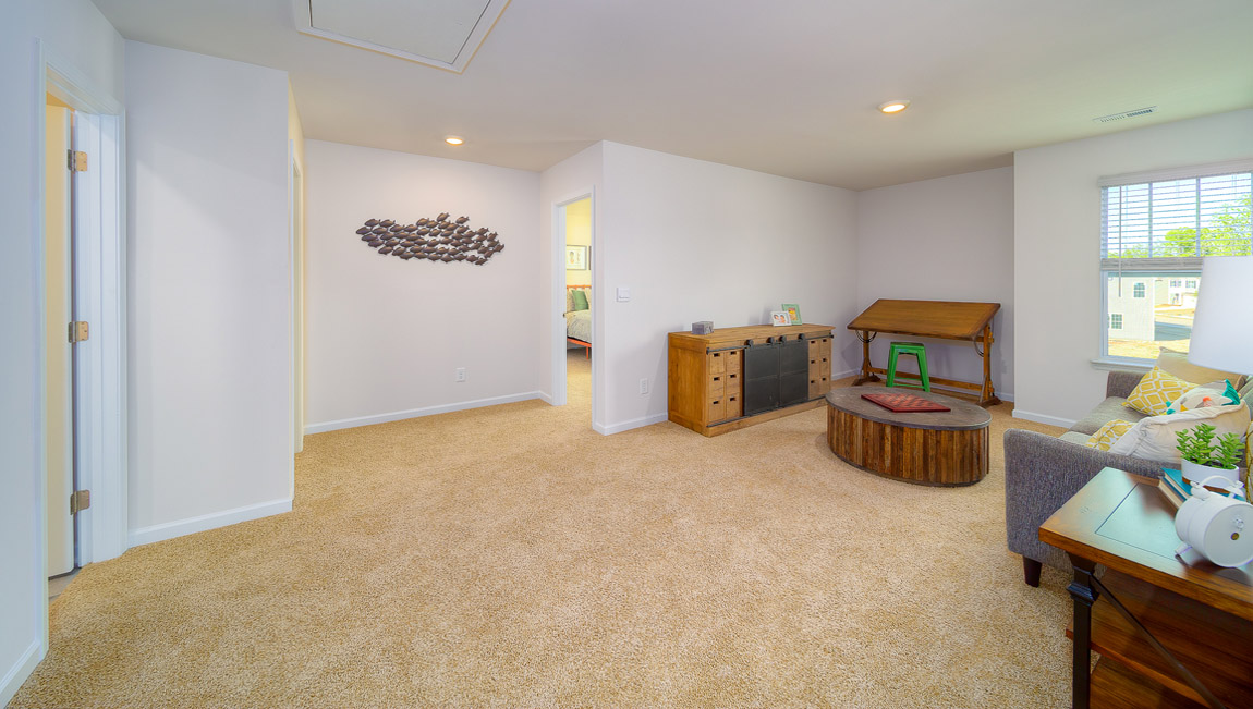 Open upstairs carpeted loft space with small window