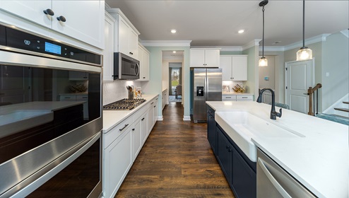 Kitchen and island with white cabinets, wood floors, and stainless steel appliances