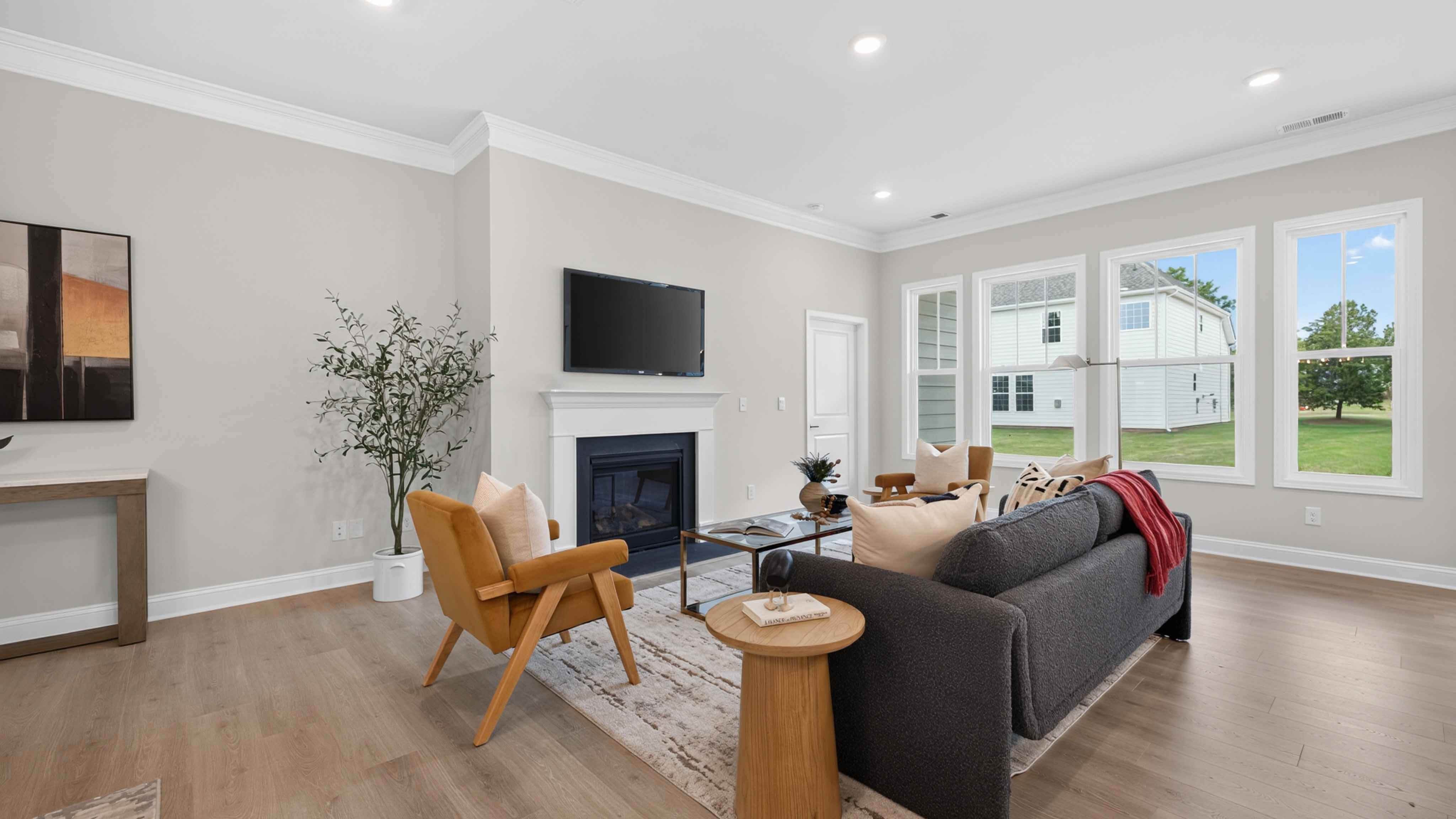 Open living room with wood floors, three windows, and fireplace