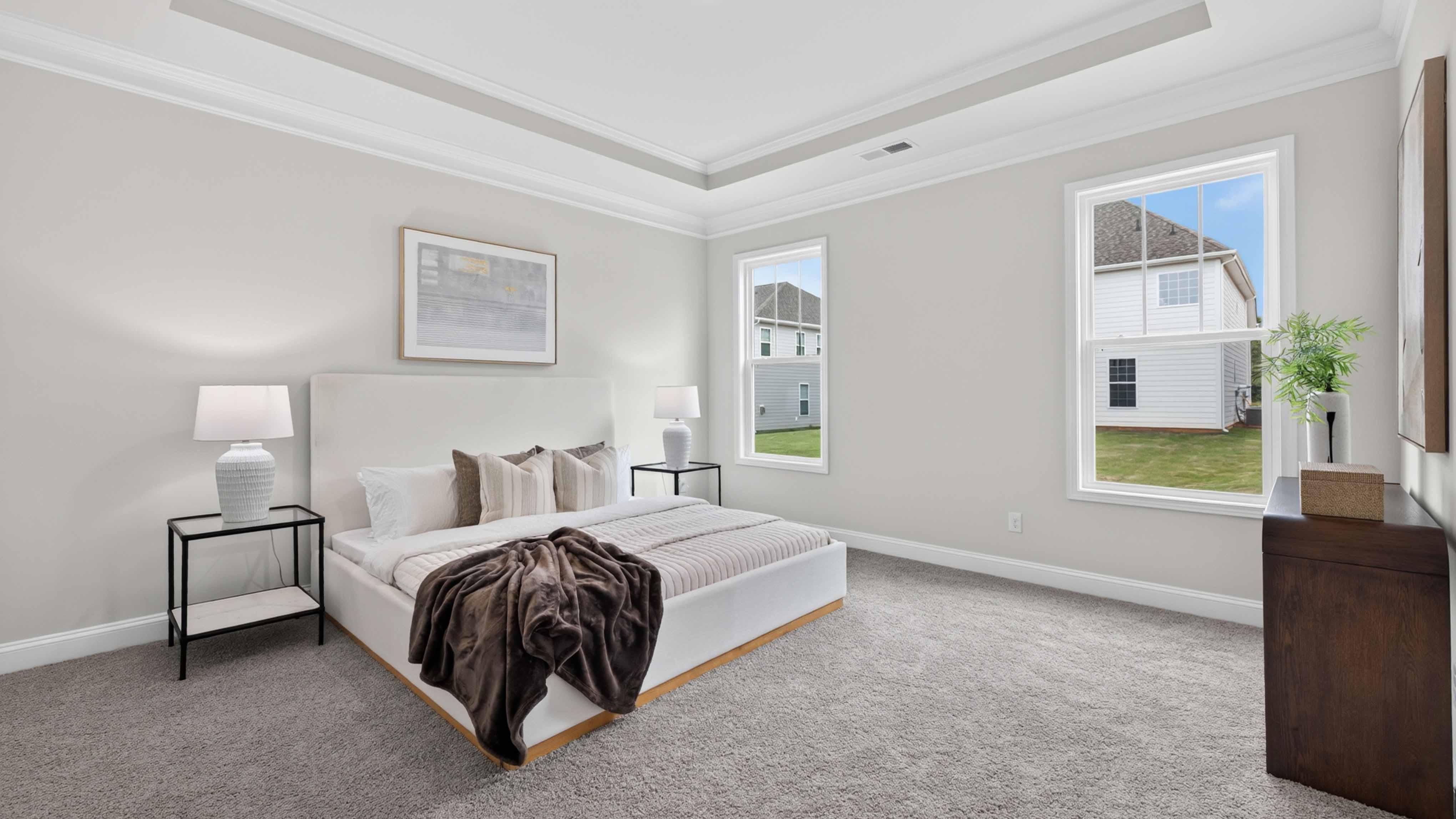 Primary bedroom with wood floors, and two large windows