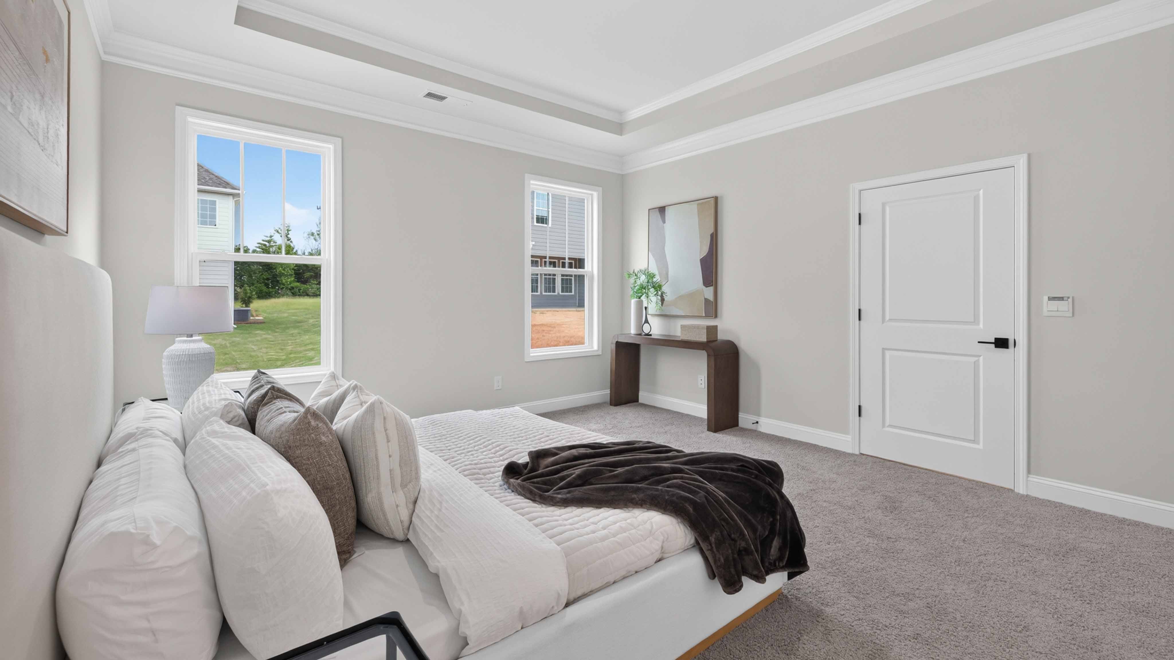 Primary bedroom with wood floors, and two large windows